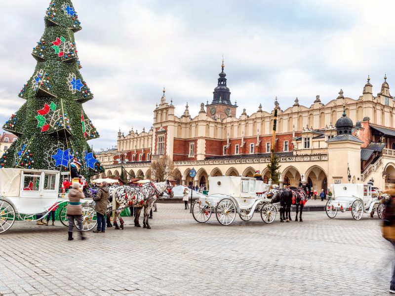 Fantastic view of the Christmas, New Year's Fair in KRAKOW. Main Market Square and Sukiennice (The Cloth Hall) in Krakow, Poland, Europe. Horse carriage.